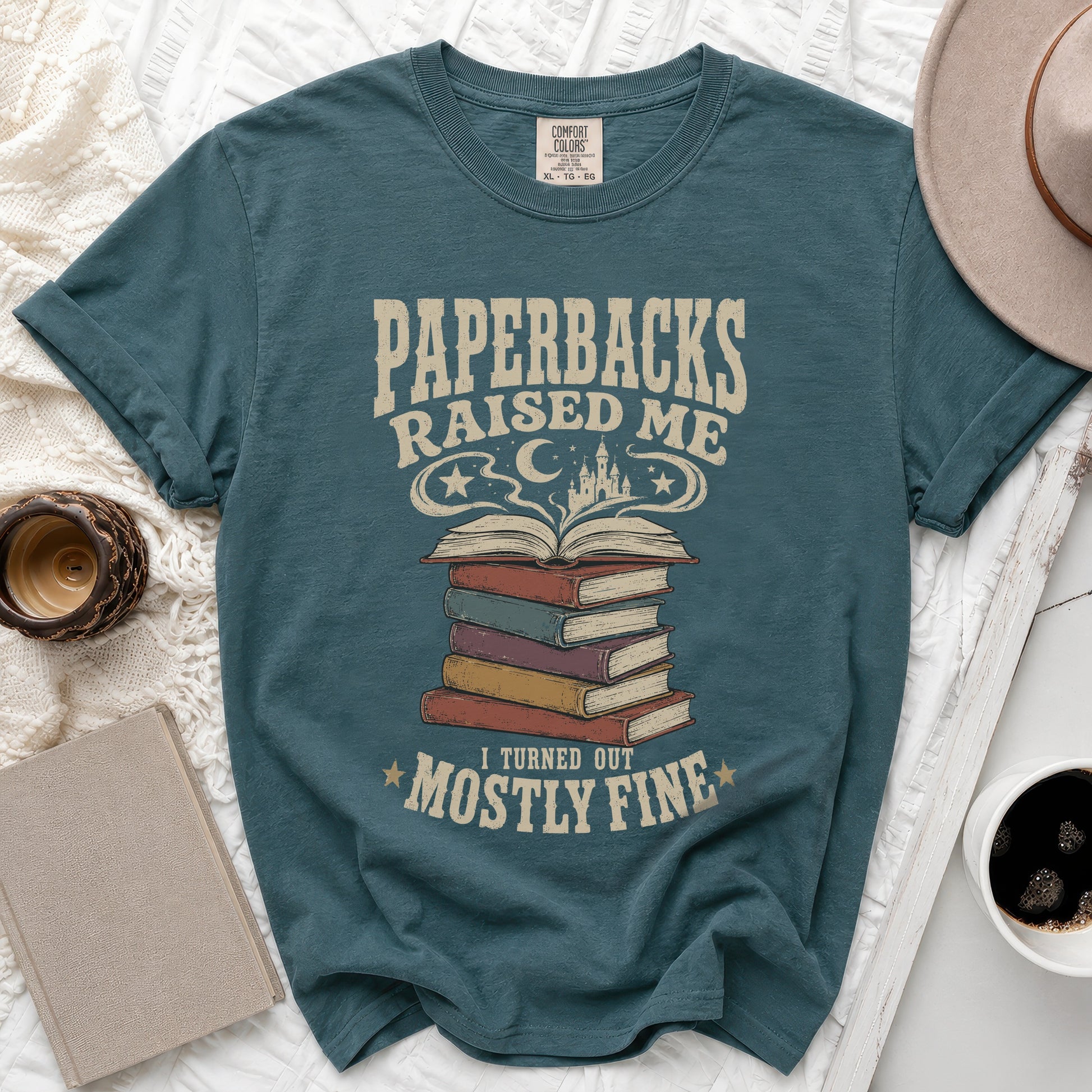 Teal t-shirt with "Paperbacks Raised Me I Turned Out Mostly Fine" text and book graphic.