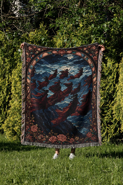 A person is holding up a large, colorful, and intricate rug with a floral design in a grassy area surrounded by trees.