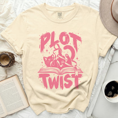 Cream t-shirt with pink "Plot Twist" graphic featuring a cat tangled in ribbon on an open book.