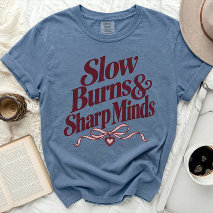 Blue t-shirt with maroon text "Slow Burns & Sharp Minds" and a pink bow.