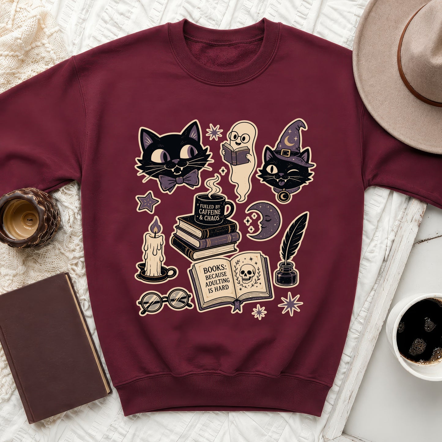 Maroon sweatshirt with Halloween-themed graphic of cats, ghost, book, and coffee cup.