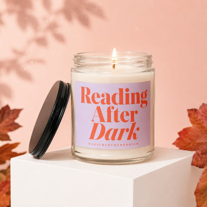Lit candle in jar inscribed "Reading After Dark" with lid beside it.