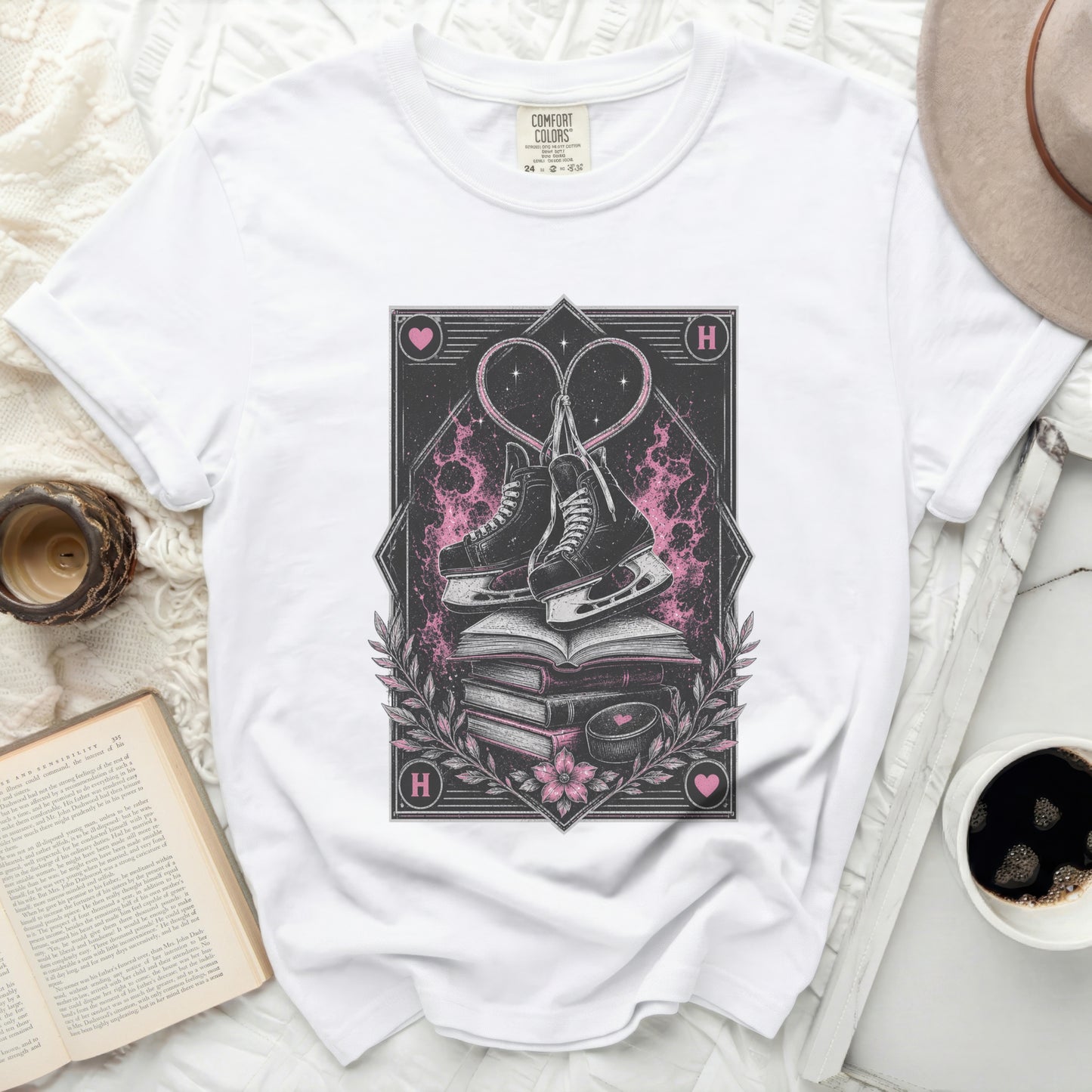 White t-shirt with heart-shaped ice skates on stacked books.
