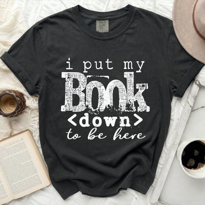 Dark gray t-shirt with white text "i put my Book <down> to be here".
