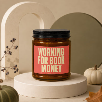 Amber jar candle with "WORKING FOR BOOK MONEY" text on coral label
