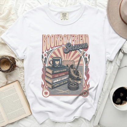 White t-shirt with "BOOKBOYFRIEND SEASON" graphic featuring books, hockey, and quotes.