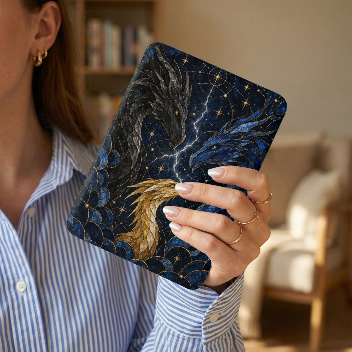 E-reader with a celestial dragon design held by a woman wearing a striped shirt.