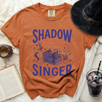 Orange t-shirt with "SHADOW Spymaster of the Night Court. SINGER" graphic.