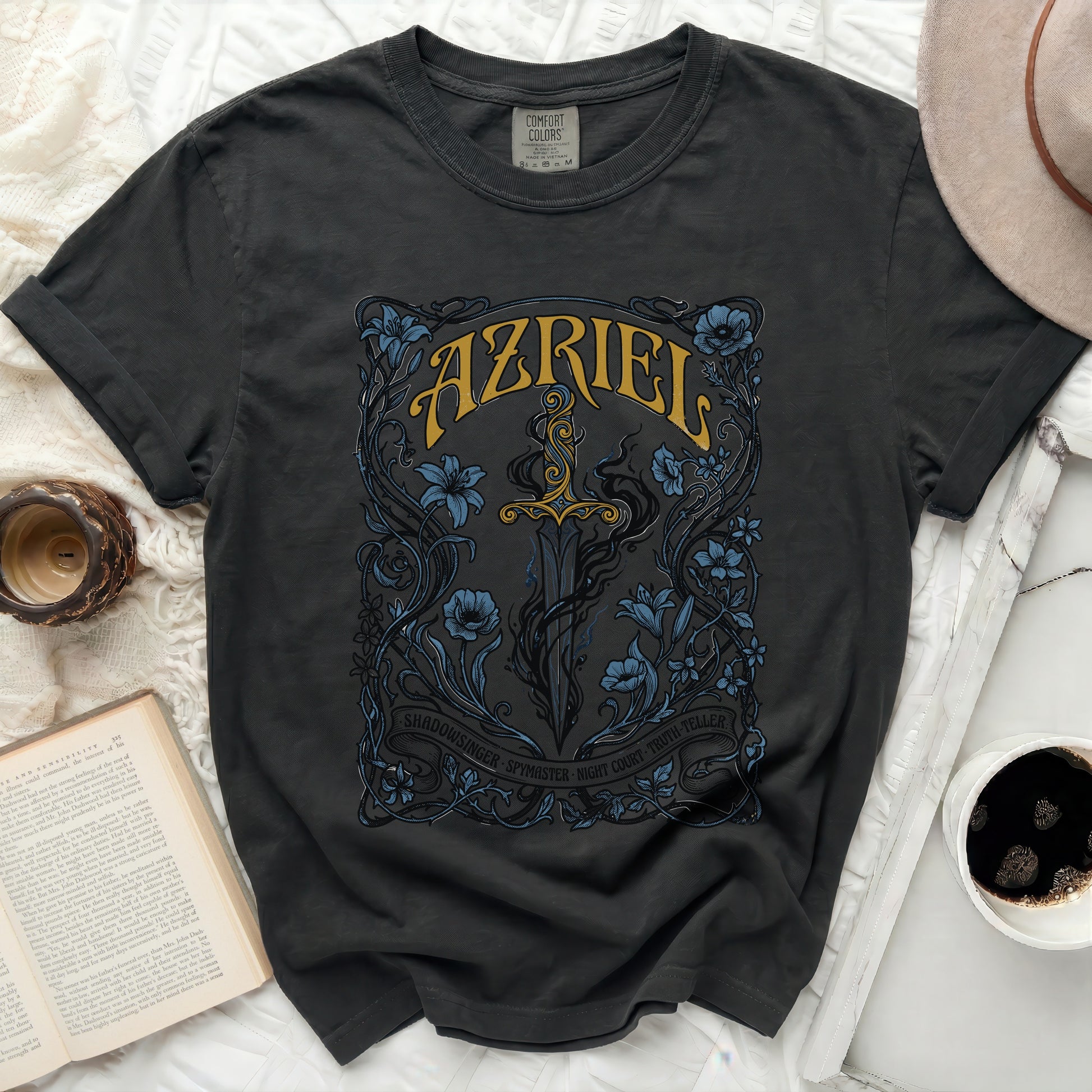 Dark t-shirt with ornate sword and floral design, reads AZRIEL SHADOWSINGER.