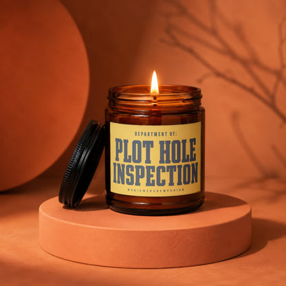 Amber glass candle with lit flame and yellow label reading "Plot Hole Inspection".