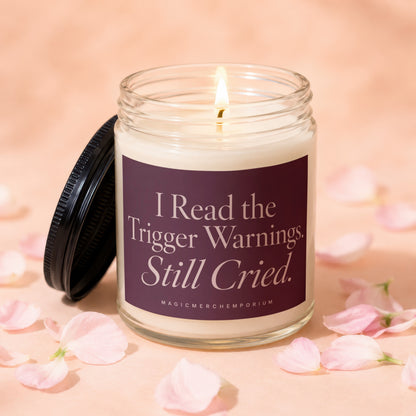 Glass candle with lit wick and label reading "I Read the Trigger Warnings. Still Cried."