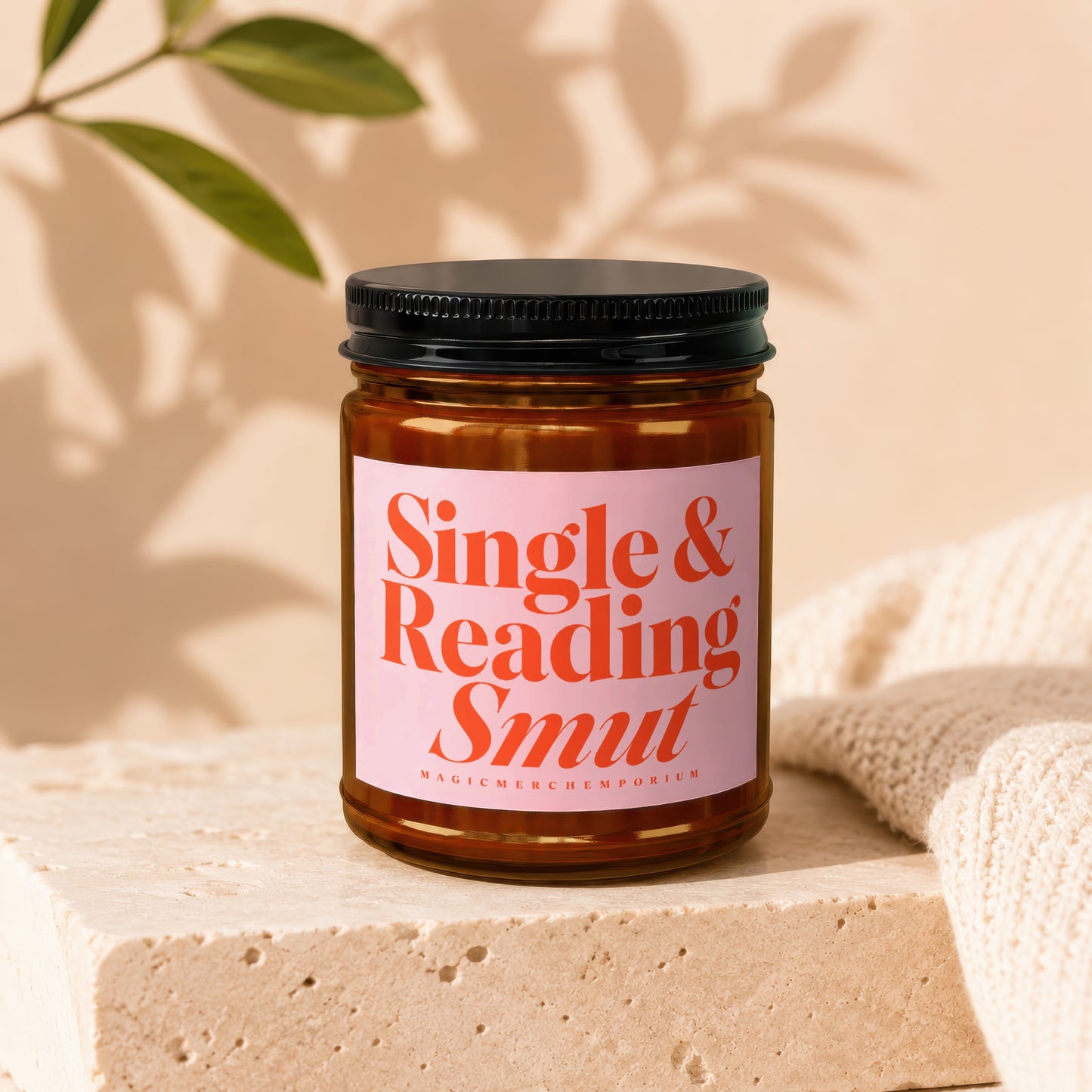 Amber jar candle with pink label reading "Single & Reading Smut".