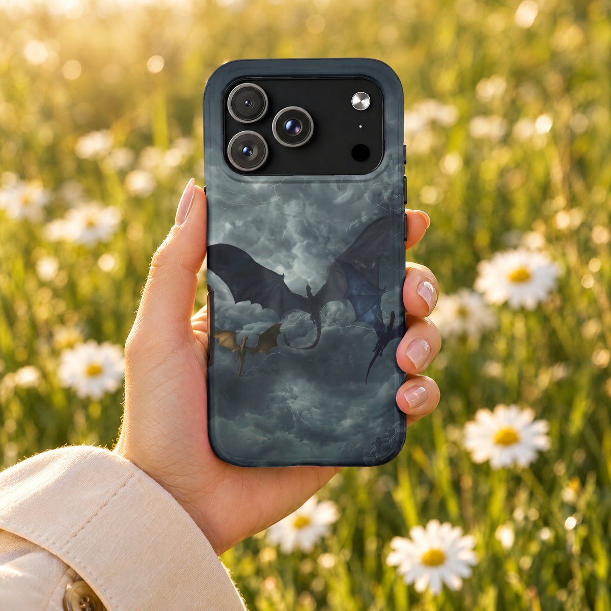 A hand holds a smartphone with a dragon-themed case against a blurry field of white daisies.
