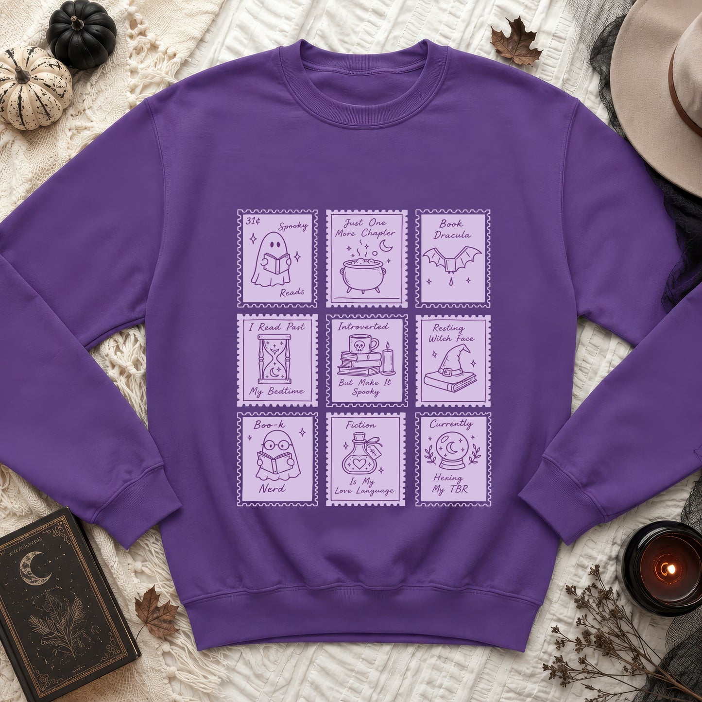 Purple sweatshirt with a graphic of nine book-themed postage stamps.