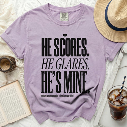 Light purple t-shirt with black text: "HE SCORES. HE GLARES. HE'S MINE."