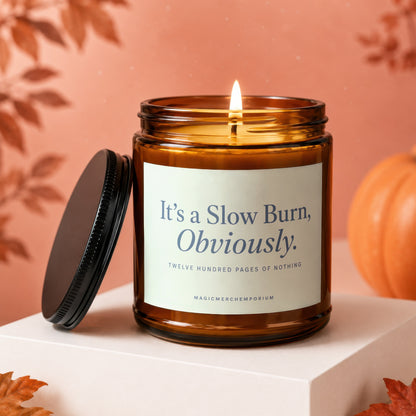 Lit amber glass candle with label reading "It's a Slow Burn, Obviously."