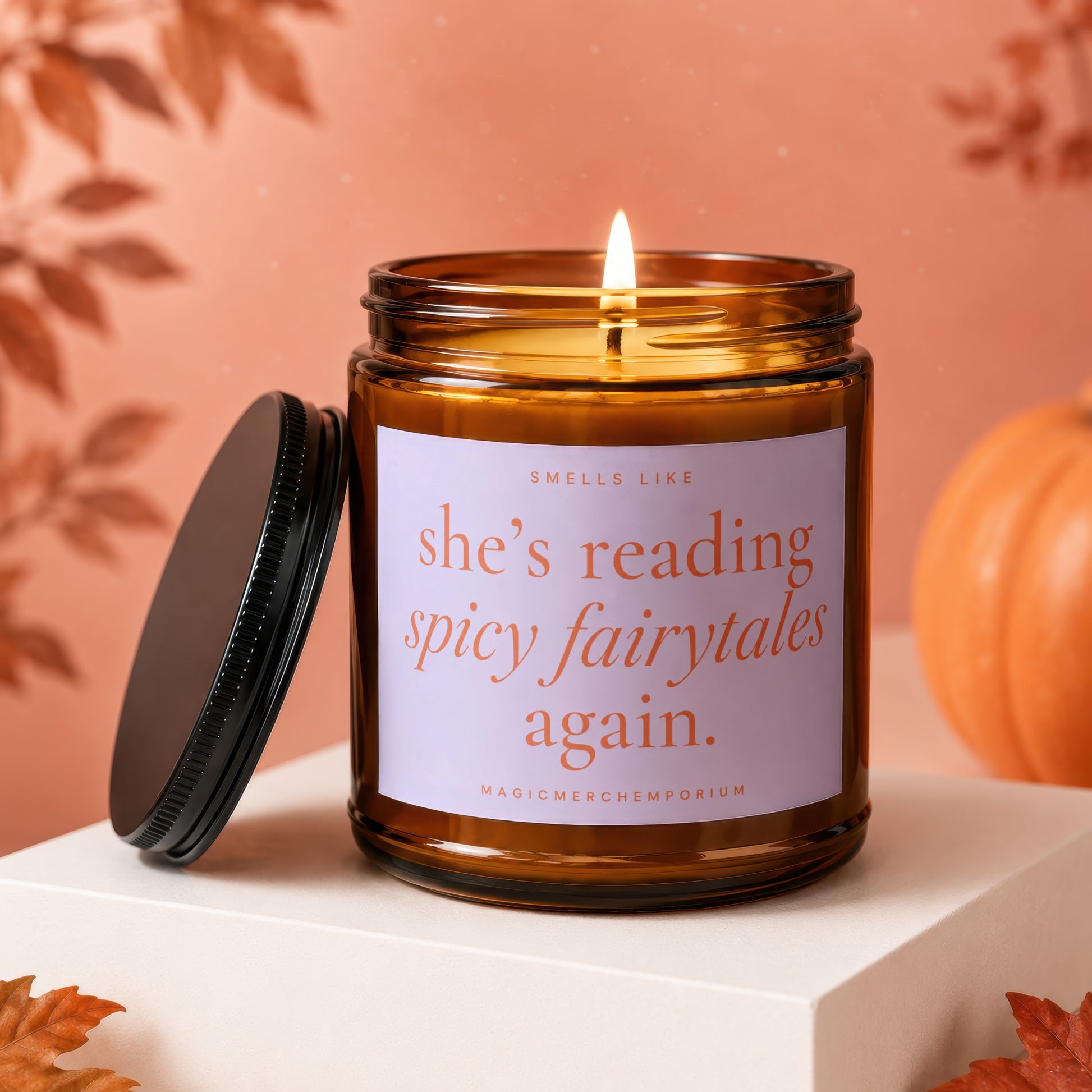 Amber glass candle with lit wick and label reading "she's reading spicy fairytales again."