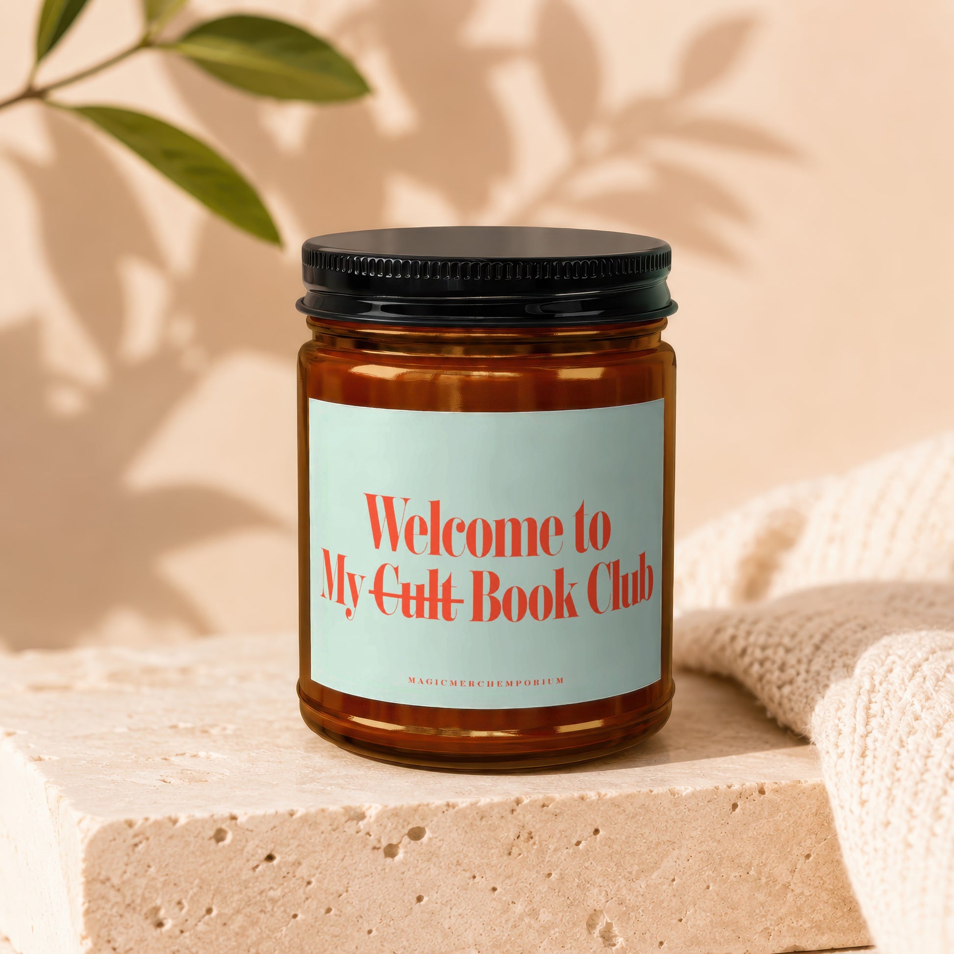 Amber jar candle with black lid labeled "Welcome to My Cult Book Club".