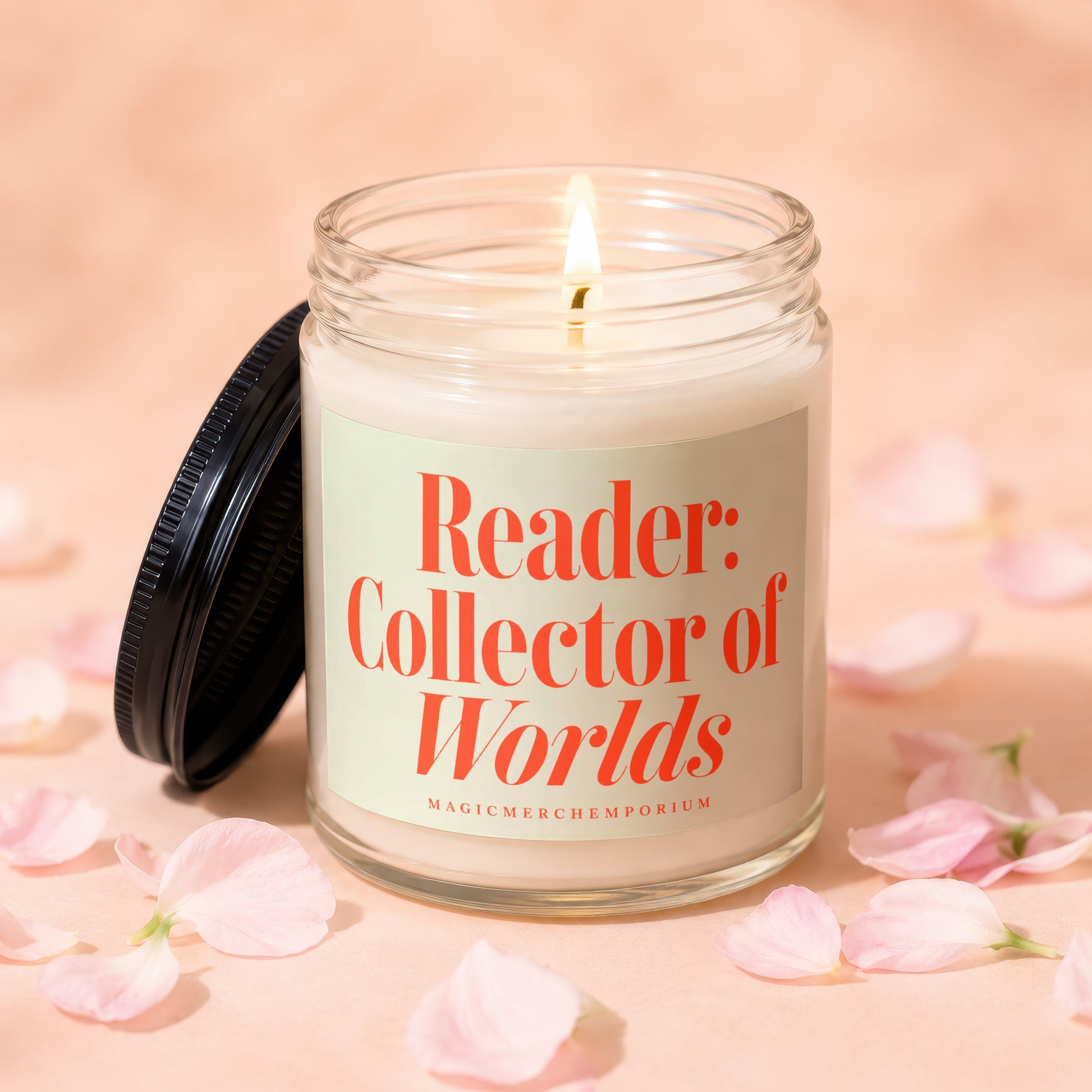 Lit glass candle with black lid, reading "Reader: Collector of Worlds"