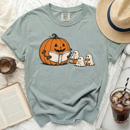 Light blue t-shirt with graphic of a pumpkin and ghosts reading a book.