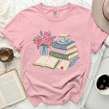 Pink t-shirt with illustration of books, teacup, flowers, and quill.