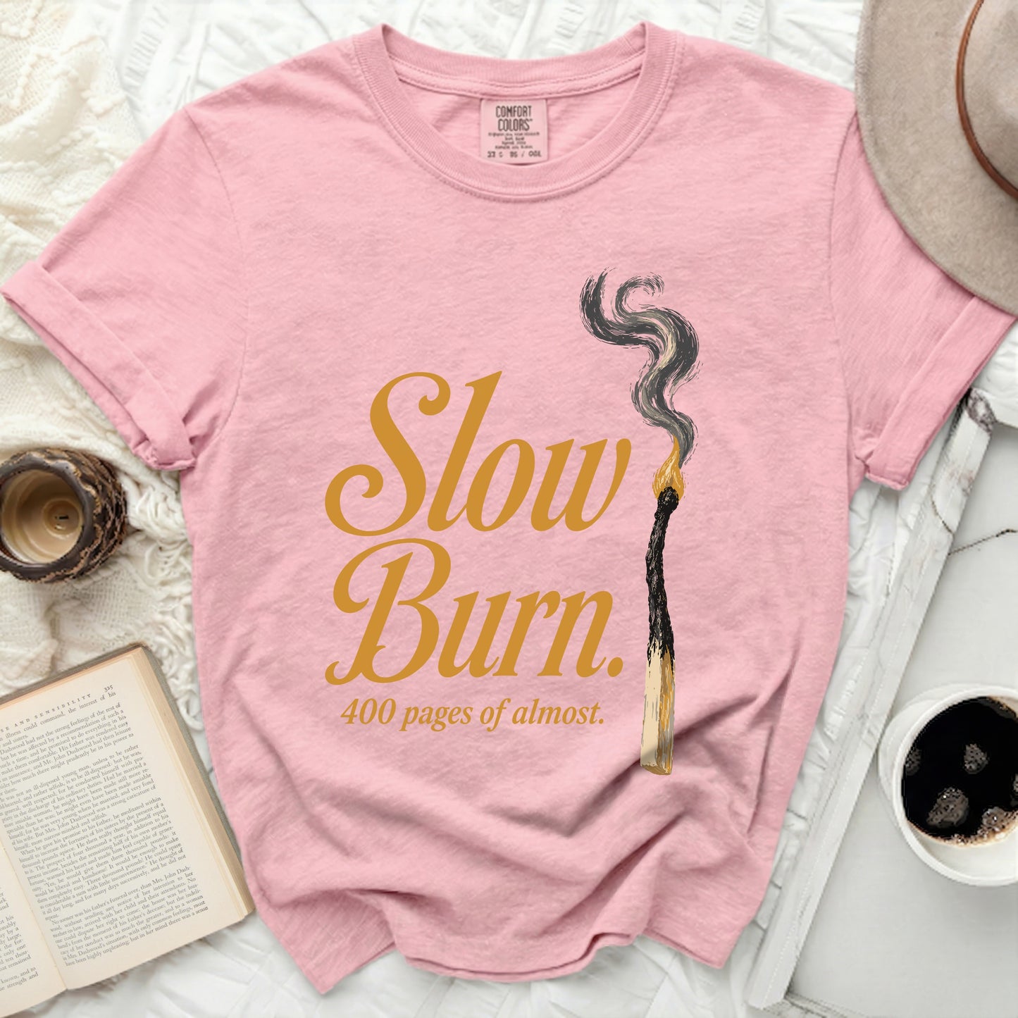 Pink t-shirt with "Slow Burn 400 pages of almost" text and burnt match graphic.