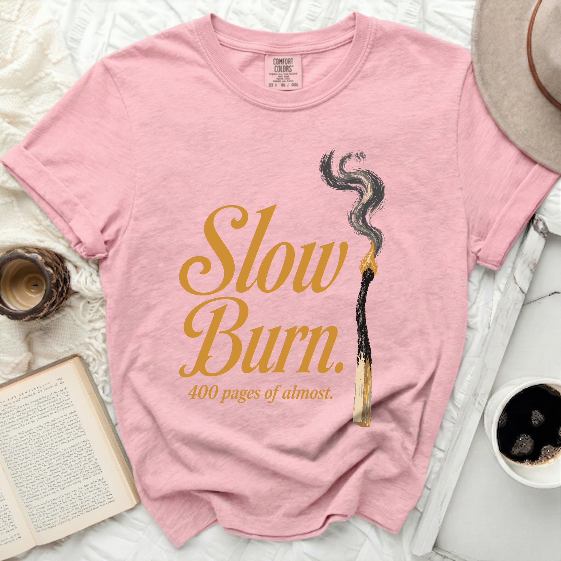 Pink t-shirt with "Slow Burn 400 pages of almost" text and burnt match graphic.