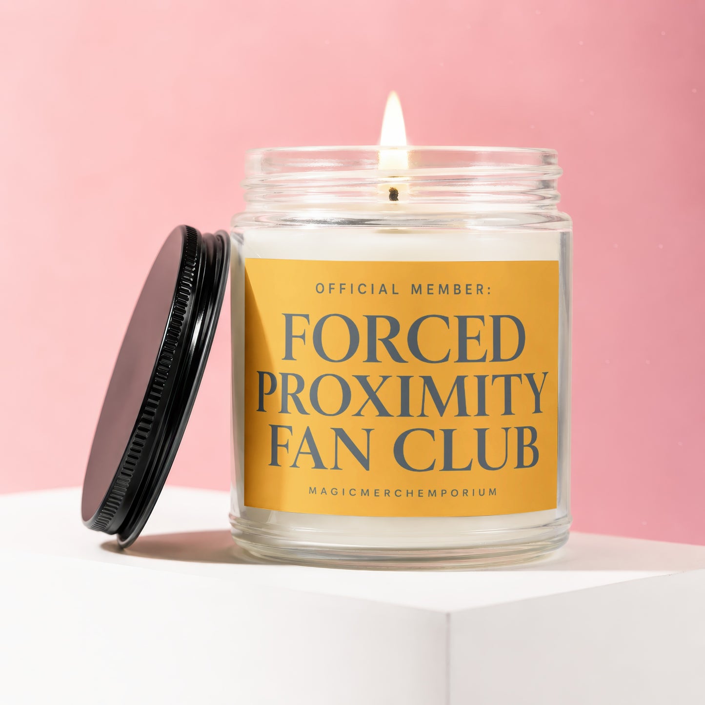 Lit candle in a glass jar with a yellow label reading "Official Member: Forced Proximity Fan Club".