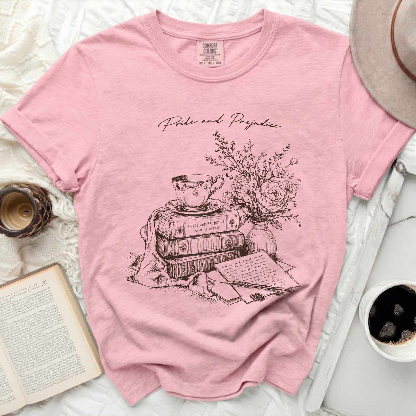 Pink t-shirt with "Pride and Prejudice" literary illustration of books, teacup, and quill.
