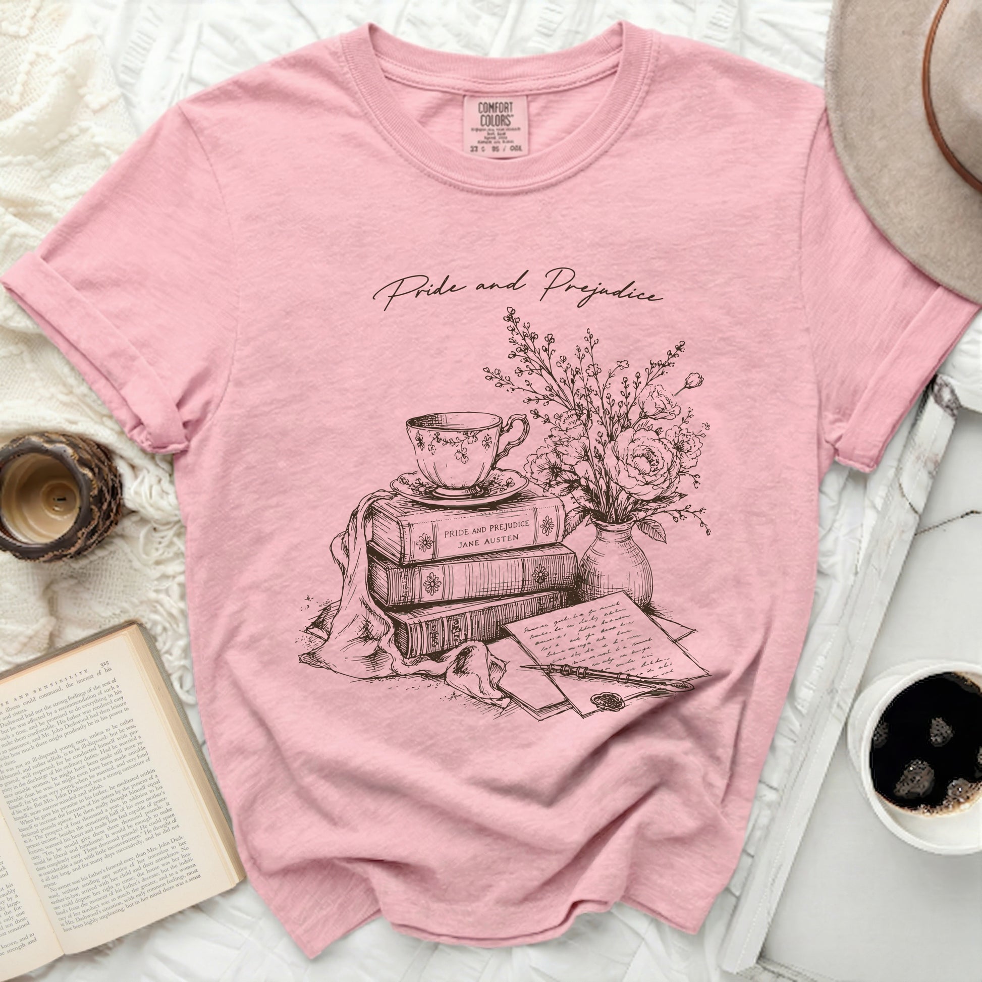 Pink t-shirt with "Pride and Prejudice" literary illustration of books, teacup, and quill.