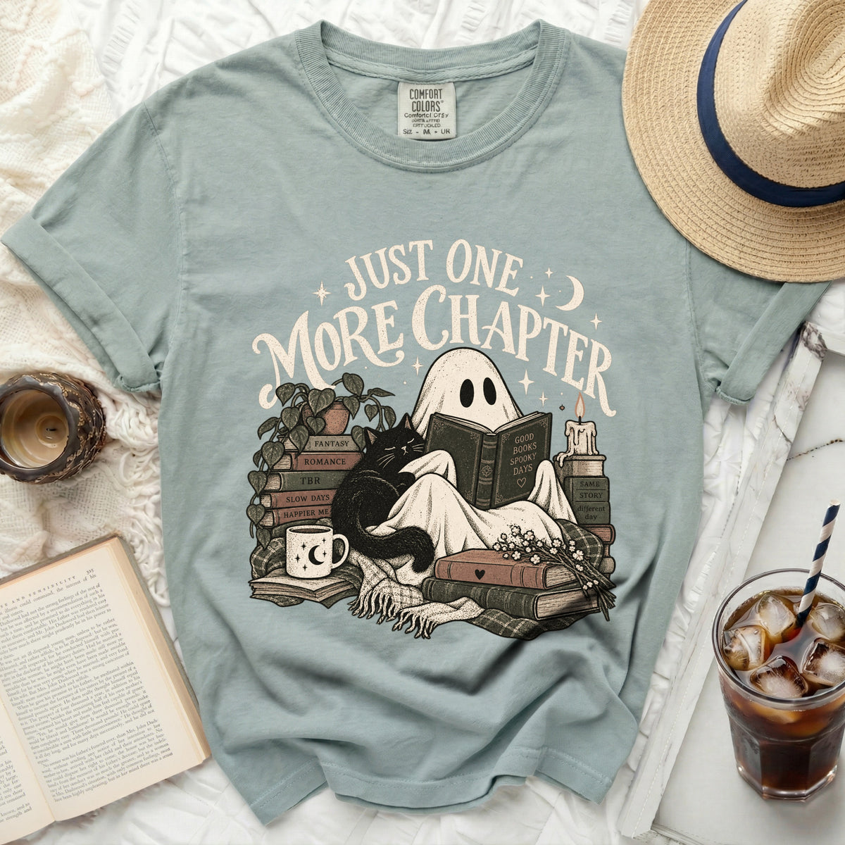 T-shirt graphic of ghost reading with cat and books, text "Just One More Chapter".