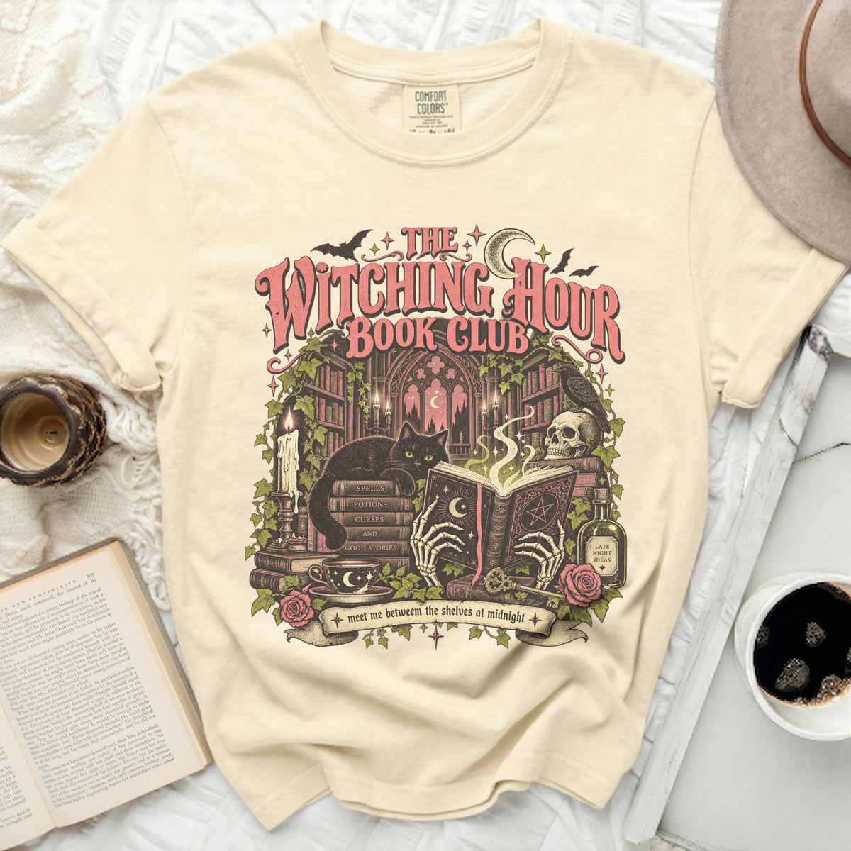 The Witching Hour Book Club graphic on a cream t-shirt with black cat, skeleton hands, books, and potion.