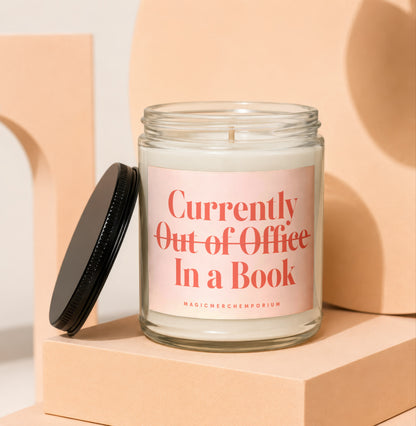 Glass candle with pink label that reads "Currently Out of Office In a Book".