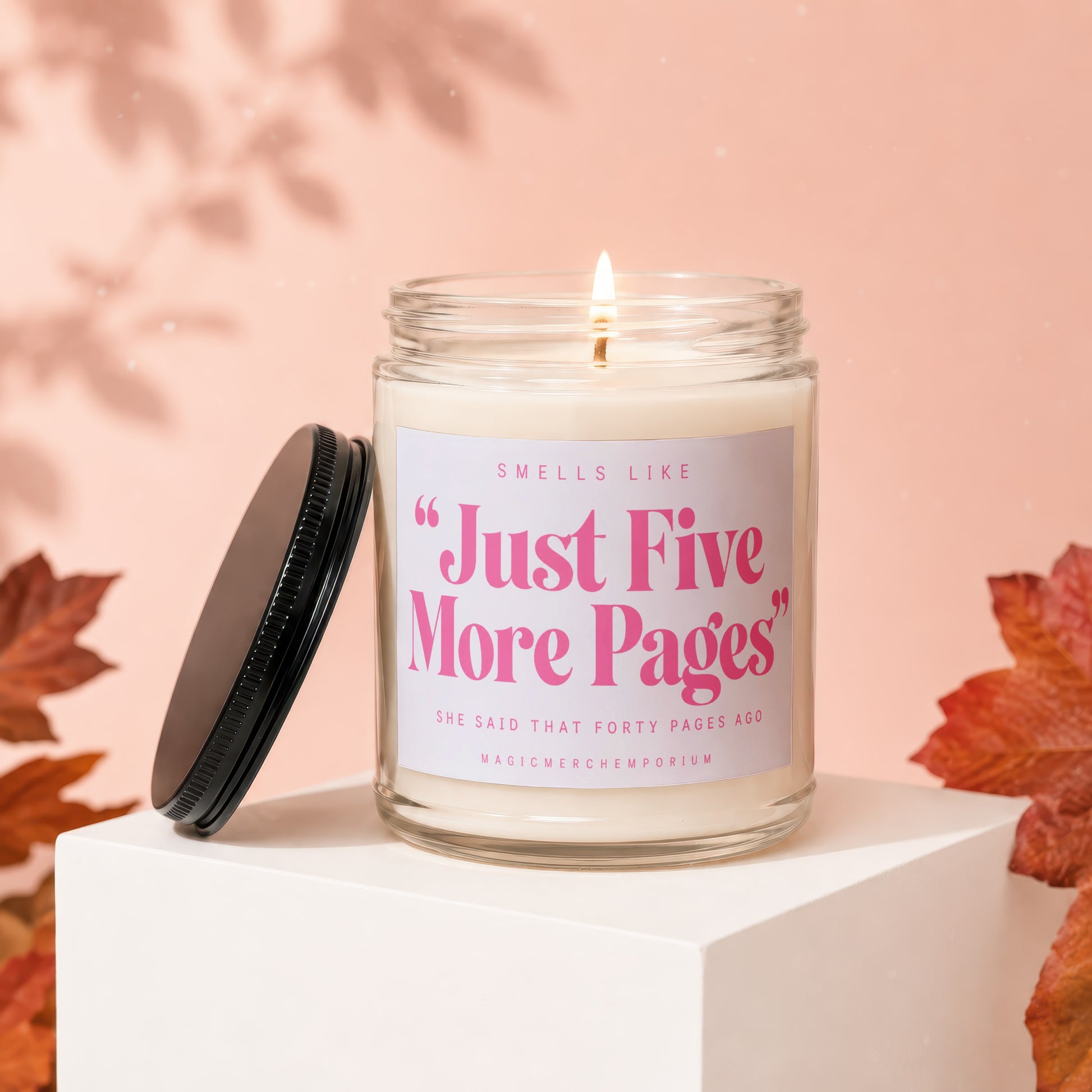 Lit candle in glass jar with "Just Five More Pages" text, black lid beside it.