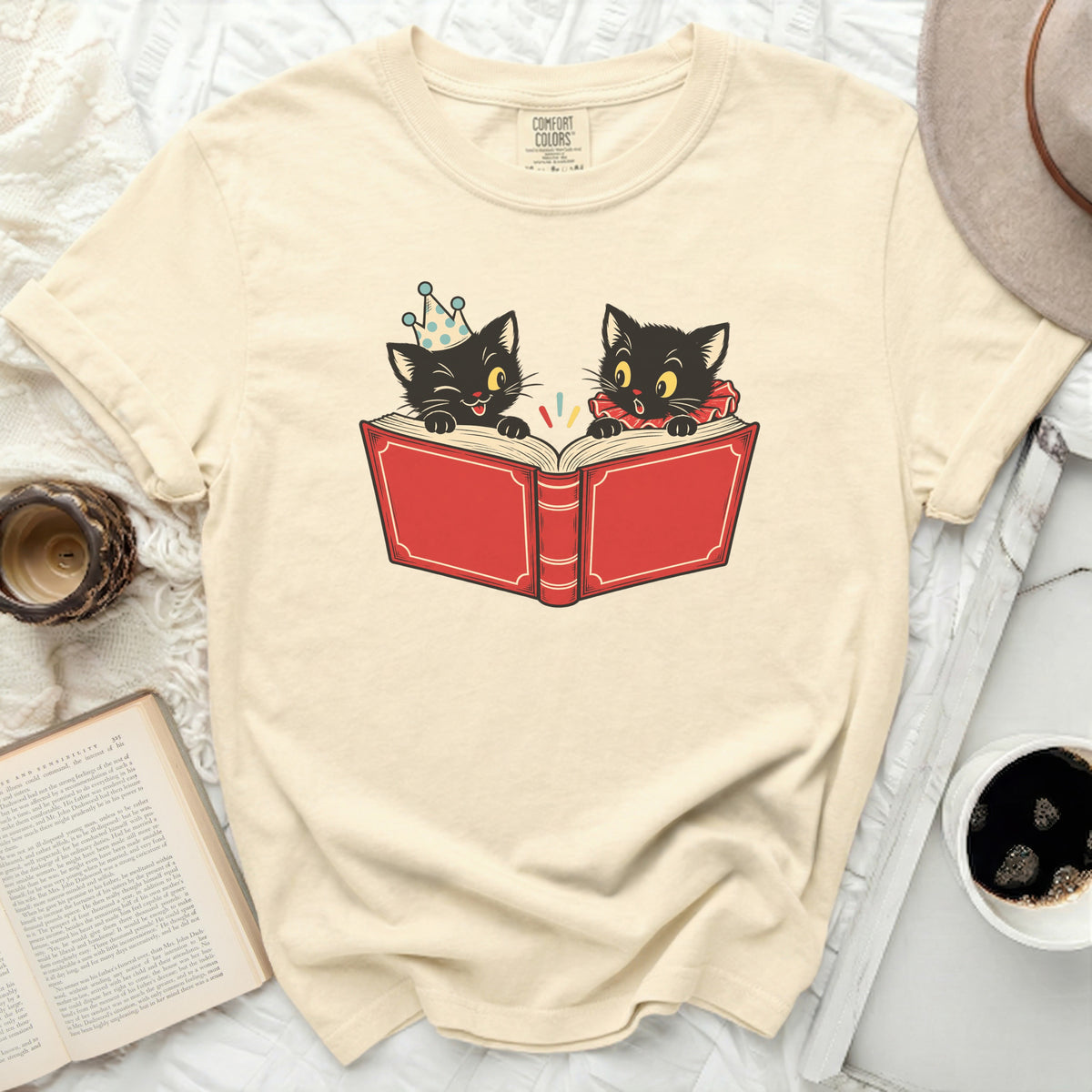 Cream t-shirt with black cats reading a red book graphic.