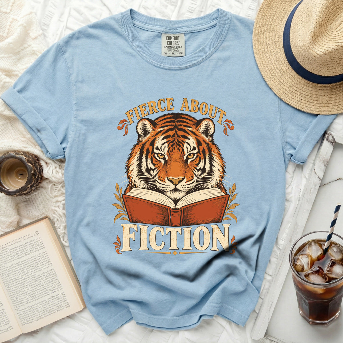 Light blue t-shirt with a tiger reading a book graphic and text "FICTION".