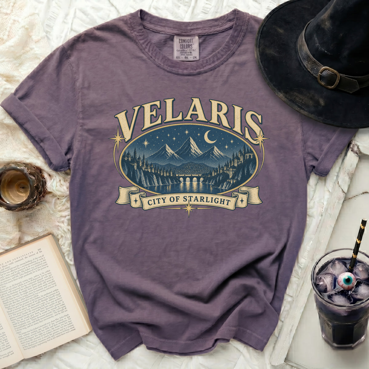 Purple t-shirt with "Velaris City of Starlight" graphic and mountainous cityscape design.