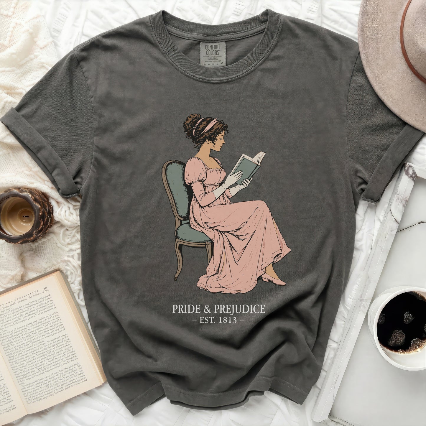 Dark gray t-shirt with illustration of a woman reading and "Pride & Prejudice est. 1813".