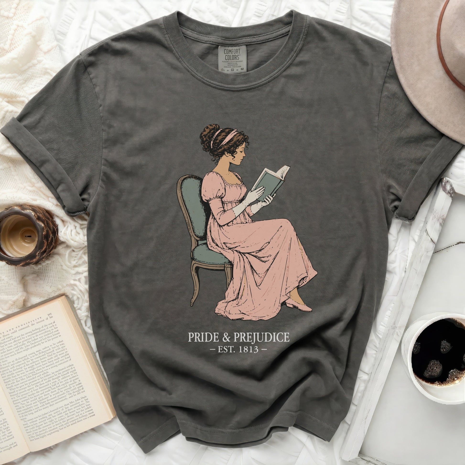 Dark gray t-shirt with illustration of a woman reading and "Pride & Prejudice est. 1813".