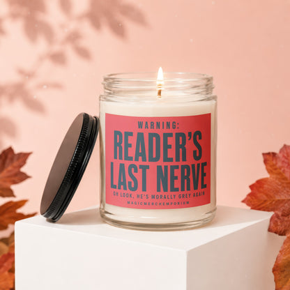 Lit candle with "READER'S LAST NERVE" label, lid off and to the side.