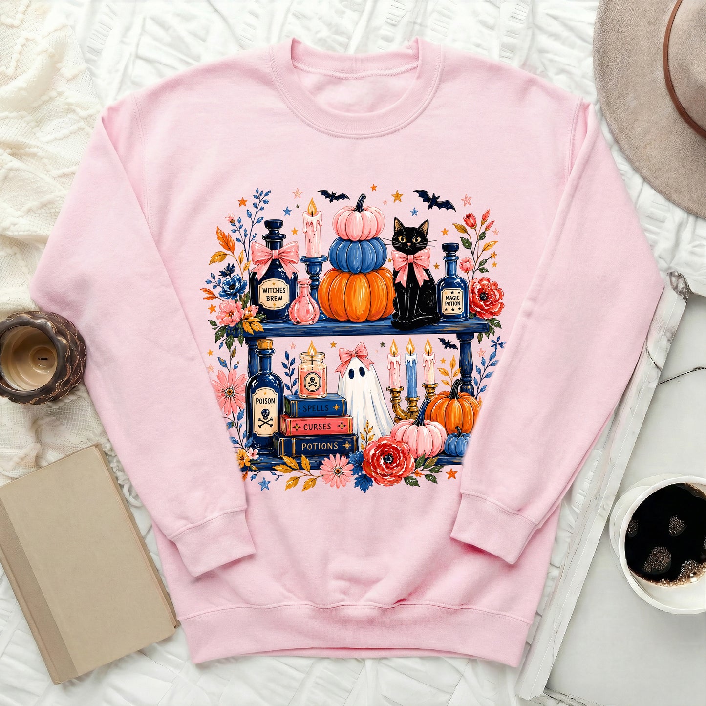 Pink sweatshirt with Halloween-themed graphic of black cat, pumpkins, ghost, and potions.