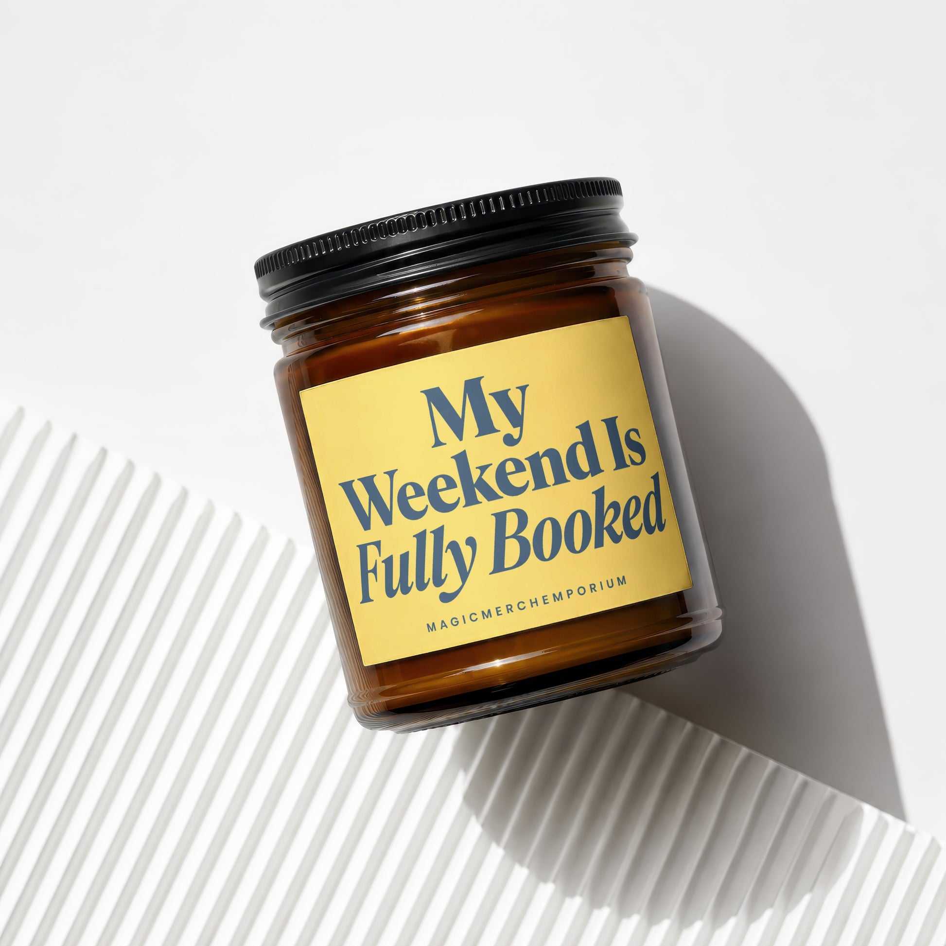 Amber jar candle with black lid and yellow label reading "My Weekend Is Fully Booked".