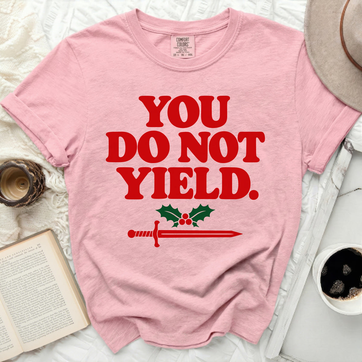 Pink t-shirt with red text "YOU DO NOT YIELD." and sword with holly.