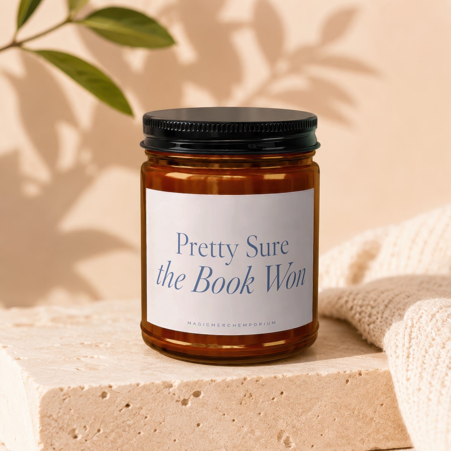 Amber jar candle with black lid, white label reads "Pretty Sure the Book Won".