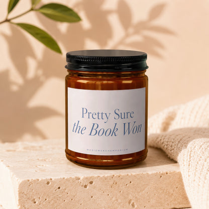 Amber jar candle with black lid, white label reads "Pretty Sure the Book Won".