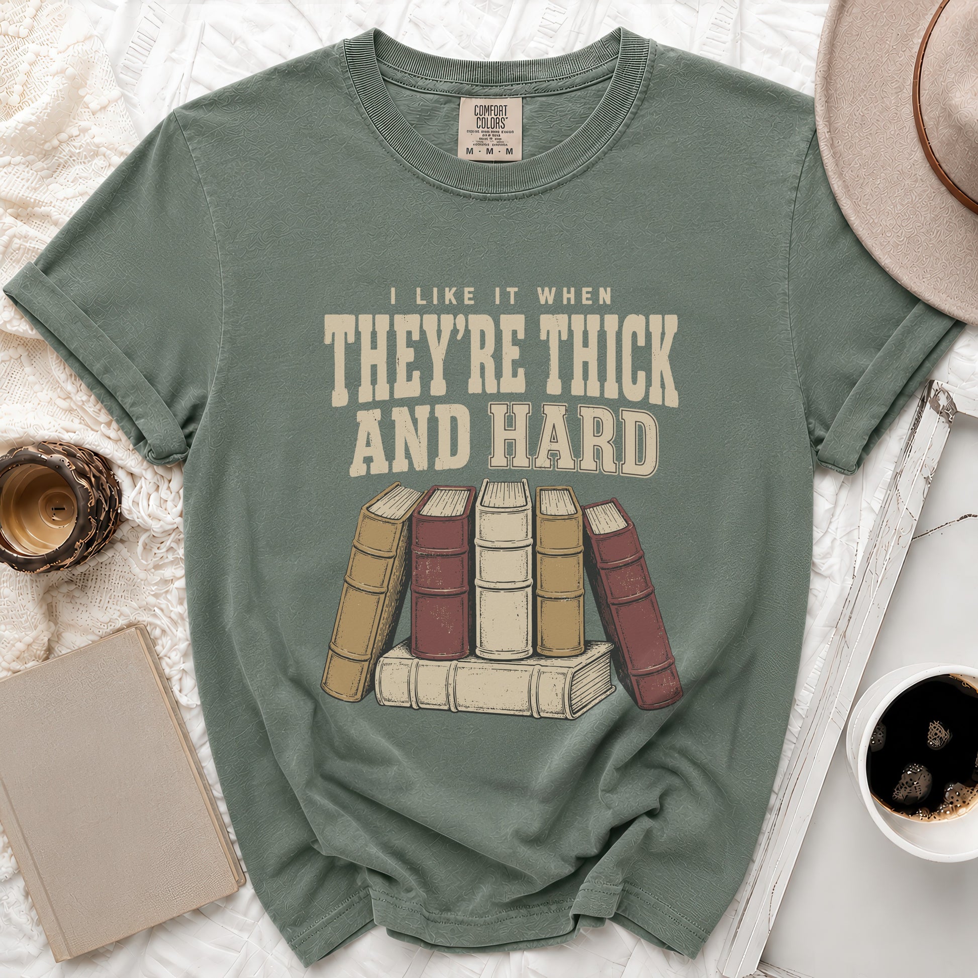 Green t-shirt with "I like it when they're thick and hard" and book graphic.