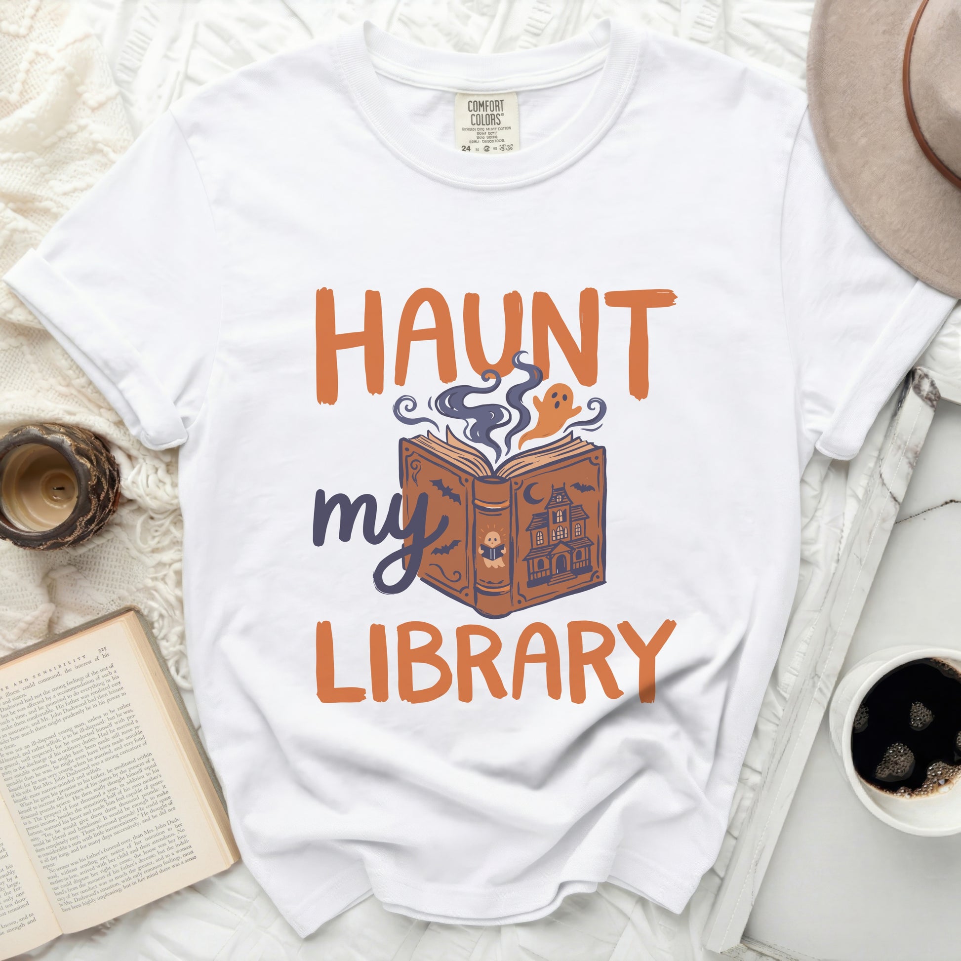 White t-shirt with orange and purple Halloween ghost and book graphic.