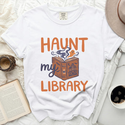 White t-shirt with orange and purple Halloween ghost and book graphic.