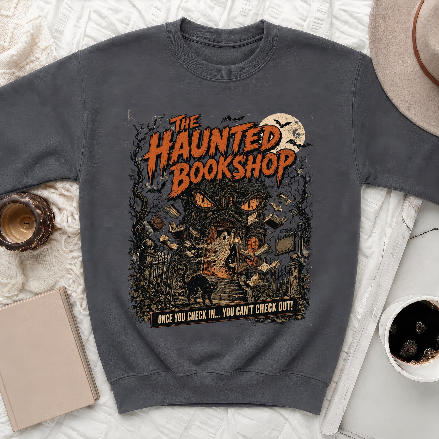 Dark sweatshirt with haunted bookshop graphic and text that reads "ONCE YOU CHECK IN... YOU CAN'T CHECK OUT!"