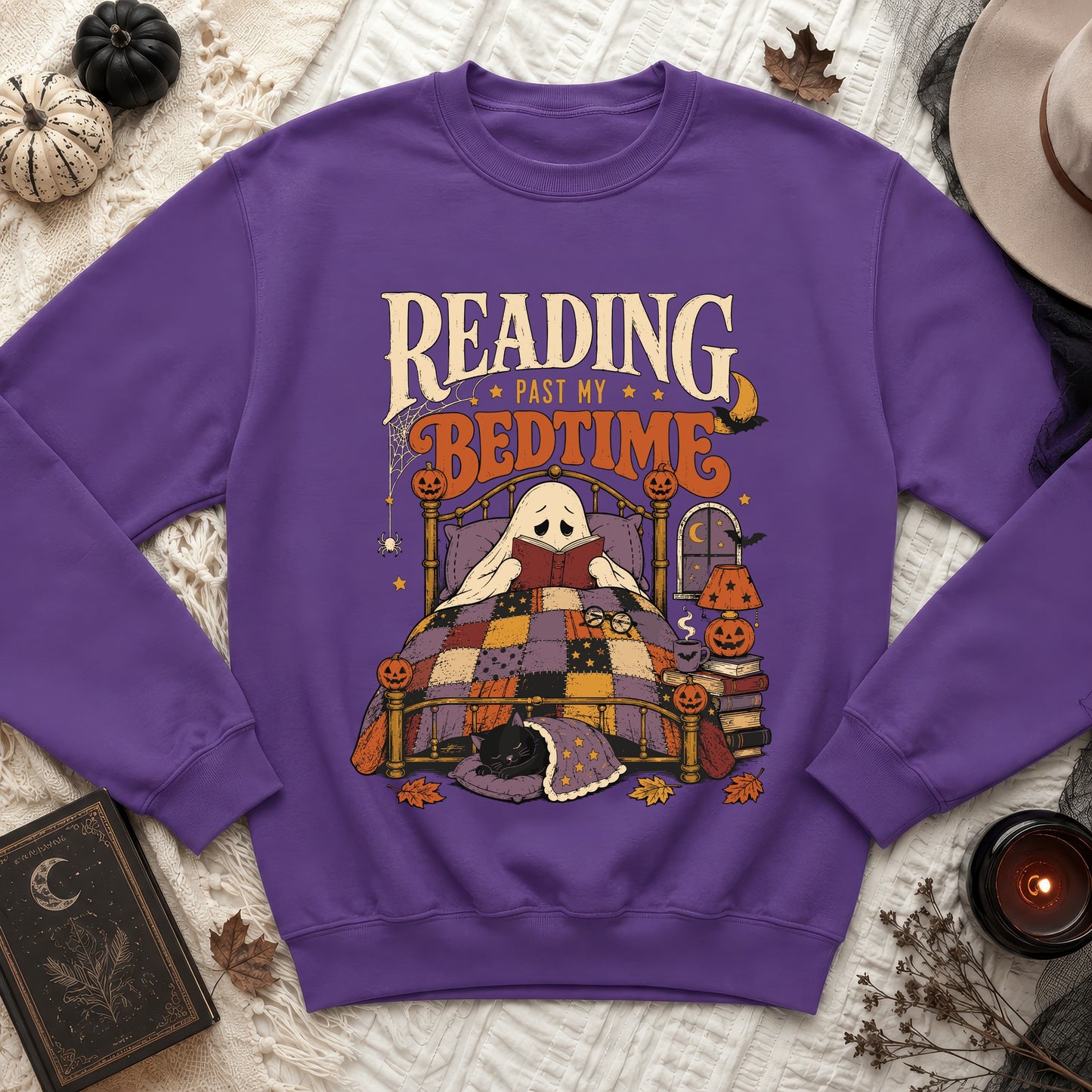Purple sweatshirt with a Halloween-themed graphic of a ghost reading in bed.